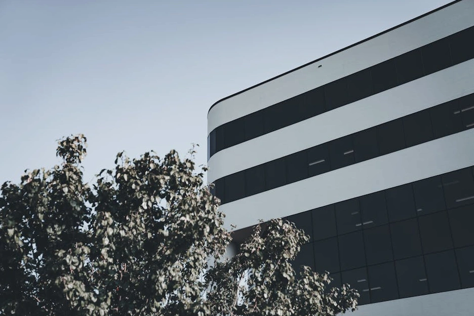 Moderno edificio per uffici con facciate in vetro che riflettono il cielo, a simboleggiare l'innovazione e la visione aziendale.